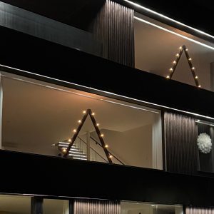 Stor belysning i glasparti. Stort fönster med ljusstake. Modern julbelysning. Design i arkitektritat hus.