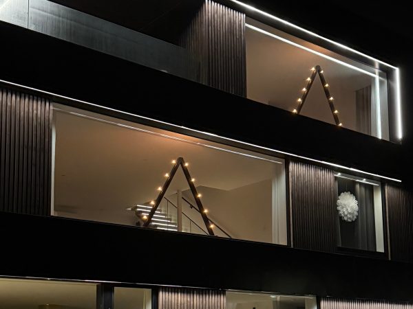 Stor belysning i glasparti. Stort fönster med ljusstake. Modern julbelysning. Design i arkitektritat hus.